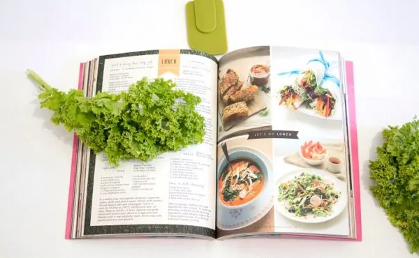Bir vegan yemek kitabı ve üzerine yerleştirilmiş taze kıvırcık marul, bitkisel tariflerle dolu ilham verici bir sayfa açık.