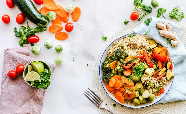 Quinoa, brokoli, havuç, biber ve kabak gibi sebzelerle hazırlanmış renkli ve dengeli bir vegan tabak.