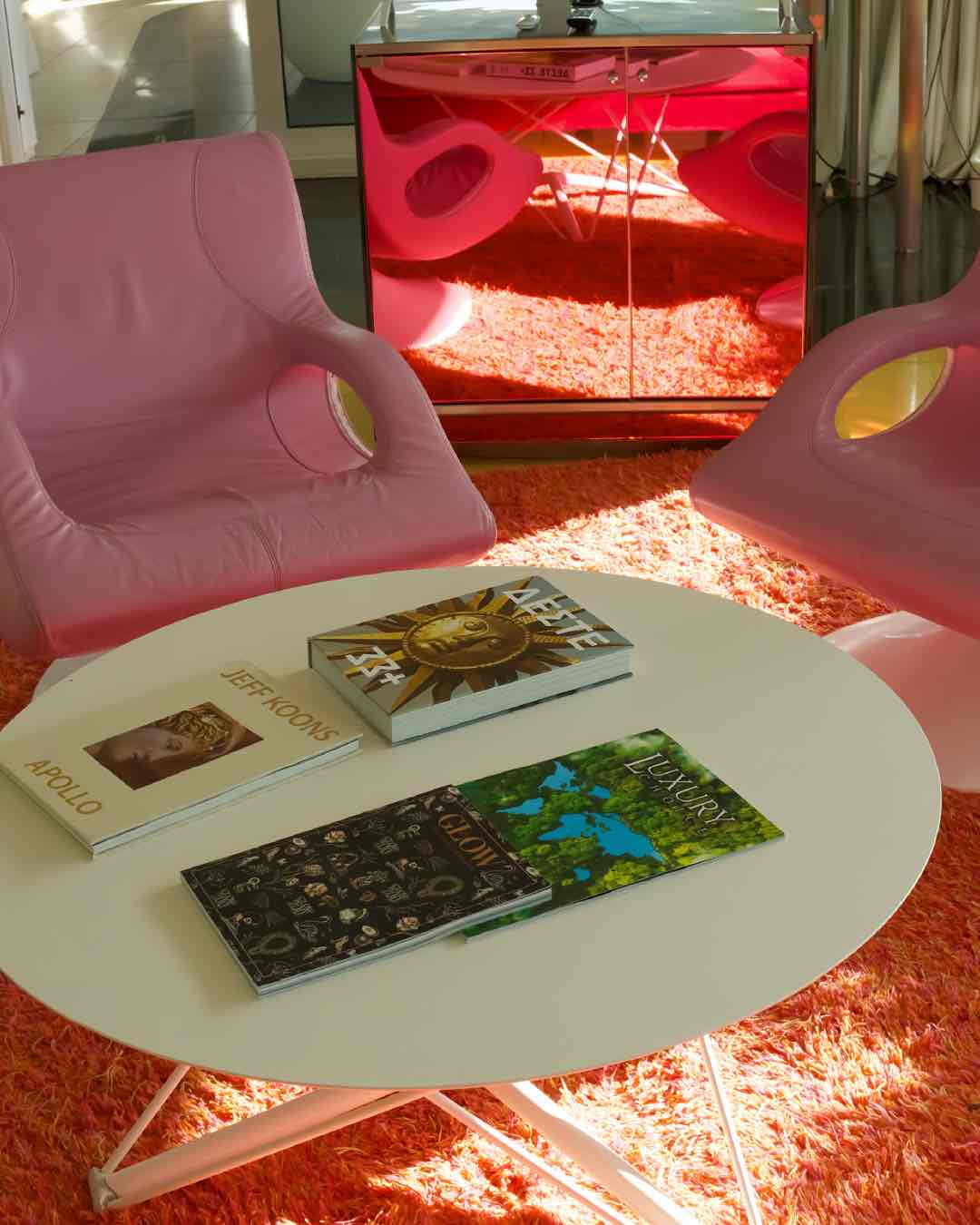 Semiramis Oteli lobisinden canlı bir köşe. Turuncu tüylü halı üzerinde, beyaz sehpa ve pop-art tarzı pembe koltuklar yer alıyor. Sehpadaki Jeff Koons kitabı, mekanın sanatsal atmosferini vurguluyor.