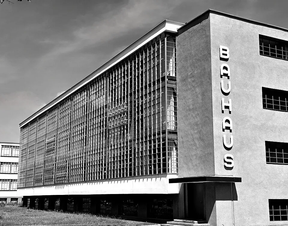 Modern mimarinin önemli yapılarından olan, Bauhaus sanat okulu binası, düşey cam panellerle kaplı uzun bir cephesi ve sağ tarafında dikey olarak büyük harflerle BAUHAUS yazısı bulunan, gri tonlardaki haliyle bir yandan çekilmiştir.