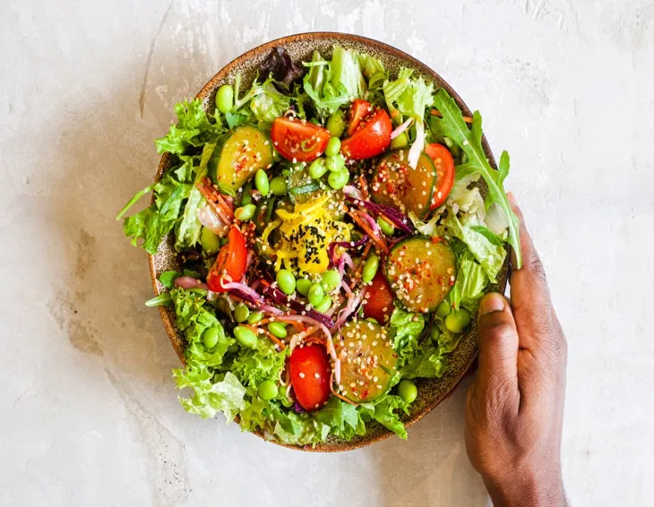 Yeşillikler, domates, edamame ve salatalıkla hazırlanmış renkli ve sağlıklı bir sebze salatası.