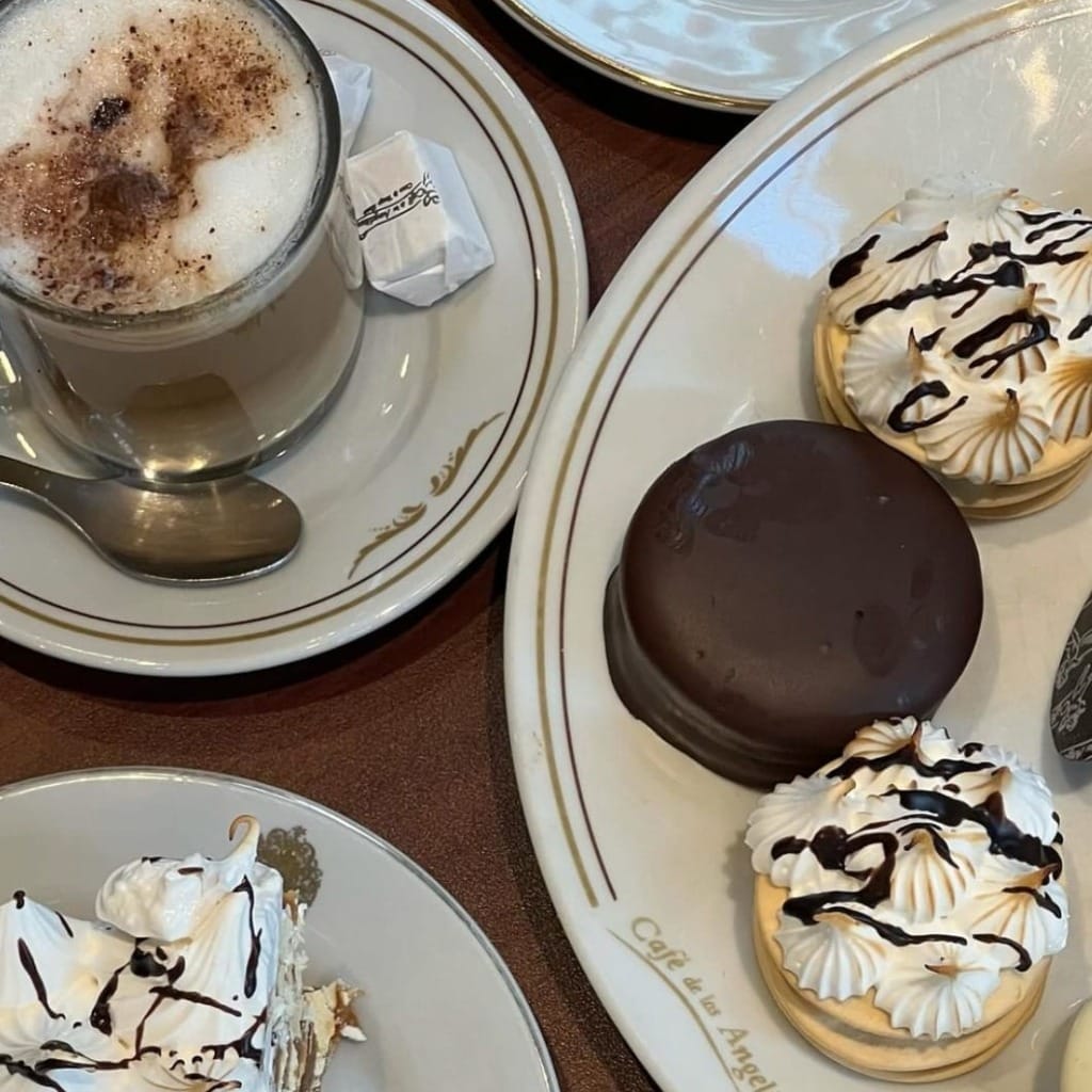 Tarihi Café de los Angelitos'ta bir masada duran köpüklü kahve ve üzeri mereng ile çikolata sosuyla süslenmiş alfajor benzeri geleneksel tatlılar, Buenos Aires'in kültürel ve gastronomik zenginliğini ve tatlılara olan tutkusunu gözler önüne seriyor.