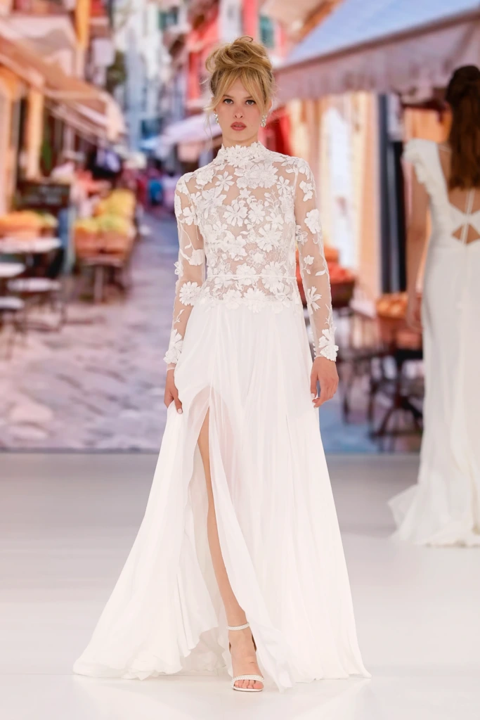 Üç boyutlu çiçek aplikeli transparan üst kısım ve yüksek yırtmaçlı uçuşan şifon etek detayına sahip Global Bridal House marka zarif gelinlik modeli.