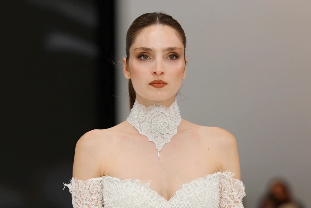 Dantel işleme yüksek yaka choker ile tamamlanmış dantelli off-shoulder gelinlik görünümü.