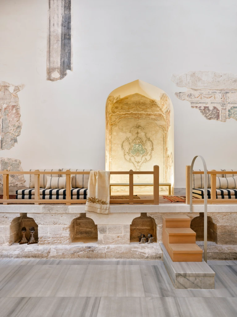 Zeyrek Çinili Hamam’ın soğukluk bölümünde yer alan taş oturma alanı, tarihi niş süslemeleri, geleneksel nalınlar ve zarif dokuma detaylarla otantik bir gelin hamamı atmosferi sunuyor.