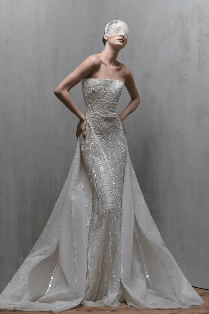 Tamamı payet işlemeli straplez couture gelinlik ve tül pelerin detaylarıyla poz veren model – ışıltılı haute couture gelinlik.