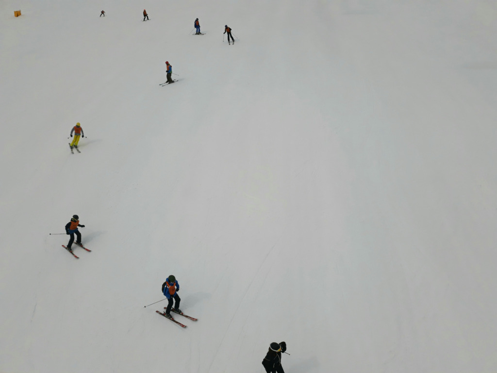 Kayak ve snowboard dersinde farklı seviyelerden sporcuların eğimde kayması