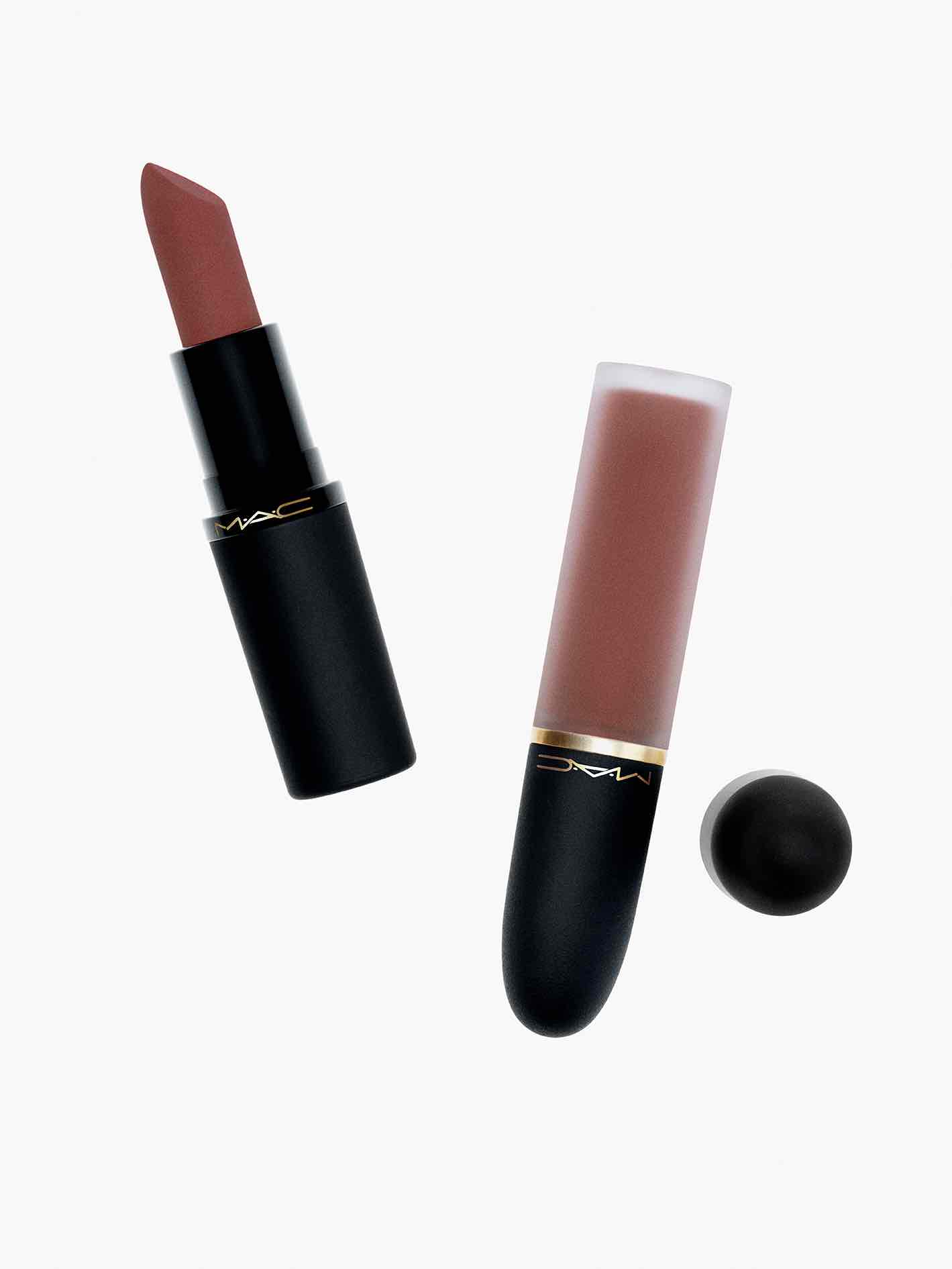 Beyaz arka plan üzerinde MAC Powder Kiss serisinden stik ve likit ruj. Gül kurusu rengindeki rujlar, mat ve pudramsı dokularını vurgulamak için siyah ambalajları açık şekilde yan yana sergileniyor.