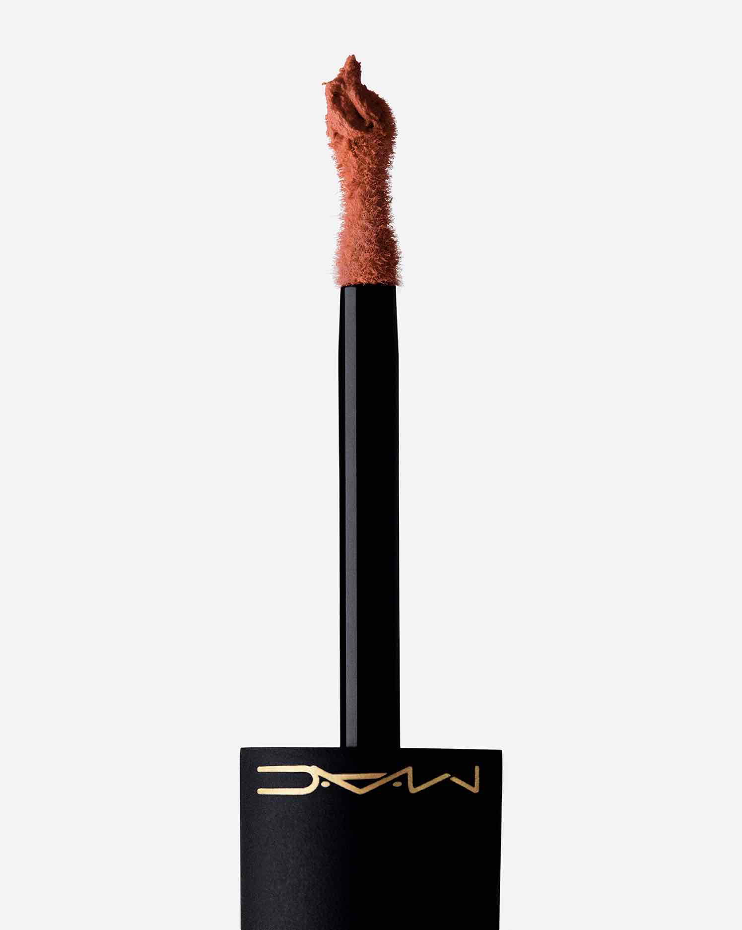 MAC Powder Kiss likit rujun kum saati şeklindeki aplikatörü, ürünün kiremit rengi ve köpüksü dokusunu sergiliyor. Siyah ambalajın üzerinde altın rengi M·A·C logosu görünüyor.