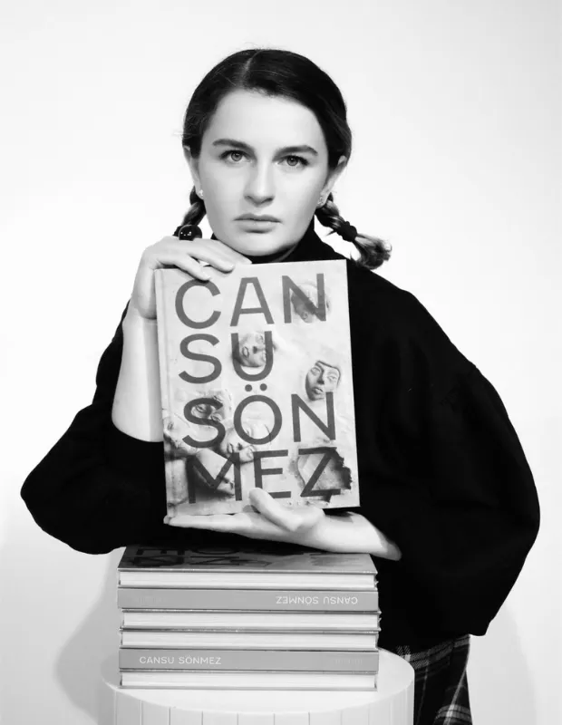 Siyah beyaz portrede, saçları iki örgü yapılmış genç bir kadın, üzerinde soyut yüz figürleri ve Cansu Sönmez yazısı olan bir sanat kitabını ve altındaki benzer kitap yığınını kucaklarken doğrudan kameraya ciddi bir ifadeyle bakıyor; bu yeni kültürel gelişme Mart ayı dikkat çekenleri arasında yer alıyor.