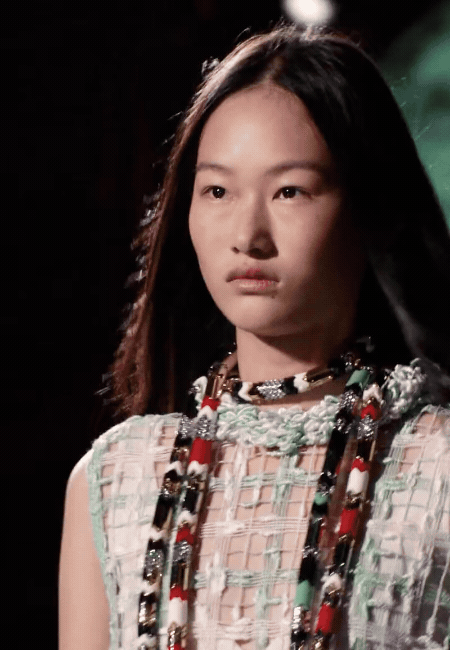 2026 İlkbahar/Yaz moda trendlerini yansıtan soğuk pastellerden nane yeşili dokulu bir üst giyen model, parlak kırmızı, siyah ve gümüş detaylı çok katlı kolyeleriyle yüksek enerjili renkler ile yumuşak tonlar arasındaki dengeyi gözler önüne seriyor.