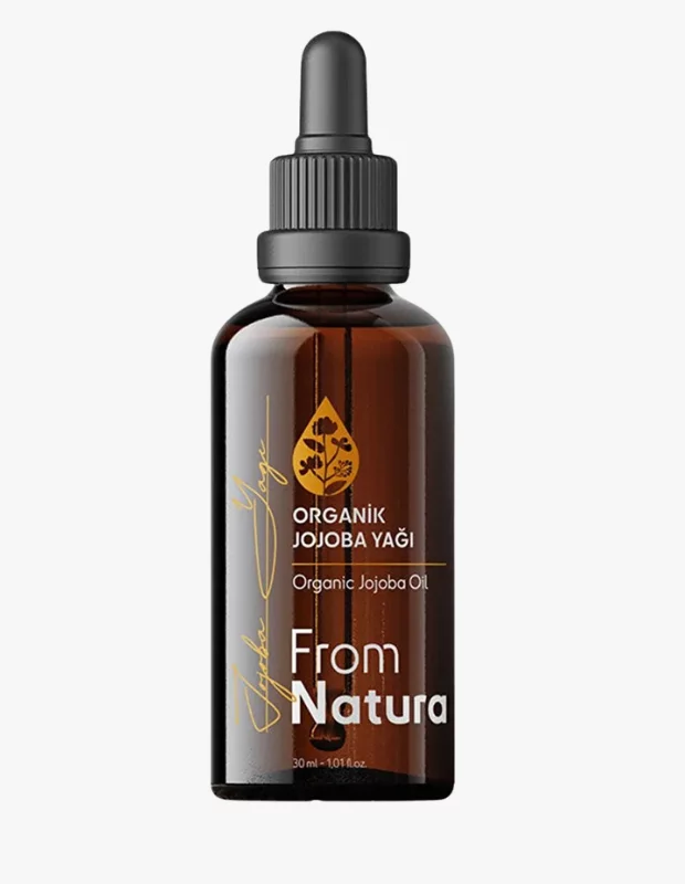 Beyaz bir zeminde duran, kehribar rengi camdan yapılmış, siyah damlalık kapaklı ve üzerinde ORGANİK JOJOBA YAĞI ibaresi bulunan etiketiyle soğuk sıkım kalitesini yansıtan 30 ml'lik From Natura marka Jojoba Yağı şişesi, posttaki cilt bariyeri onarımı ve mucizevi faydalarına uygun olarak vurgulanıyor.