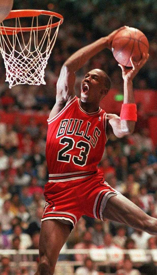 Michael Jordan, kırmızı Chicago Bulls 23 numaralı formasıyla havada coşkulu bir şekilde basketbolu potaya smaçlarken, forma giydiği yıllardaki efsanevi performansı ve kırdığı rekorları akla getiriyor.