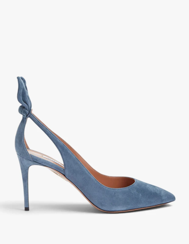 Aquazzura markasına ait, denim mavisi süet kumaştan yapılmış, sivri burunlu, ince topuklu ve arkasında şık bir fiyonk detayı bulunan bu topuklu ayakkabı, sonbahar-kış ayakkabı trendlerinin öne çıkan parçalarından biri olarak beyaz bir zeminde sergileniyor.