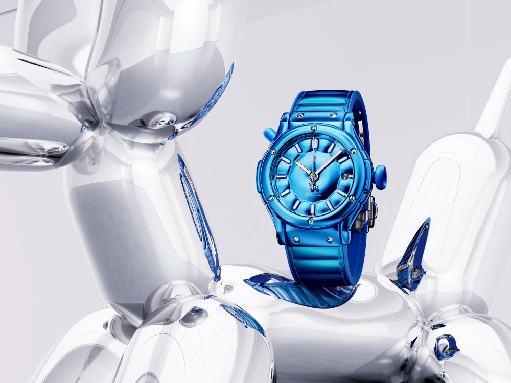 Jeff Koons'un ikonik balon köpek sanat eserini anımsatan, parlak yansıtıcı gümüş tonlarında bir heykelin üzerinde merkezlenmiş, göz alıcı parlak mavi renkte bir Hublot Classic Fusion saat, metalik ve çağdaş bir estetiği bir araya getirerek dikkat çekiyor.