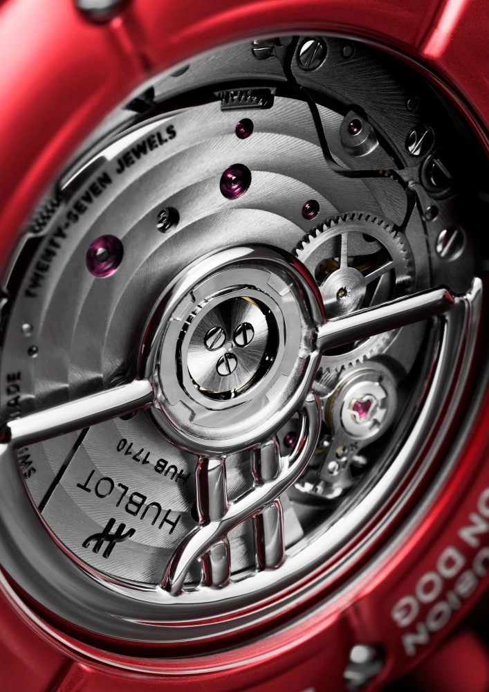Hublot Classic Fusion Balloon Dog koleksiyonundan, kırmızı kasasıyla dikkat çeken saatin iç mekanizması; hassas işçilikli gümüş renkli çarklar, 27 yakut taşı ve markanın amblemi ile HUB 1710 referans numarasının kazılı olduğu sanatsal tasarımlı rotor detayıyla zarif bir uyum sergiliyor.