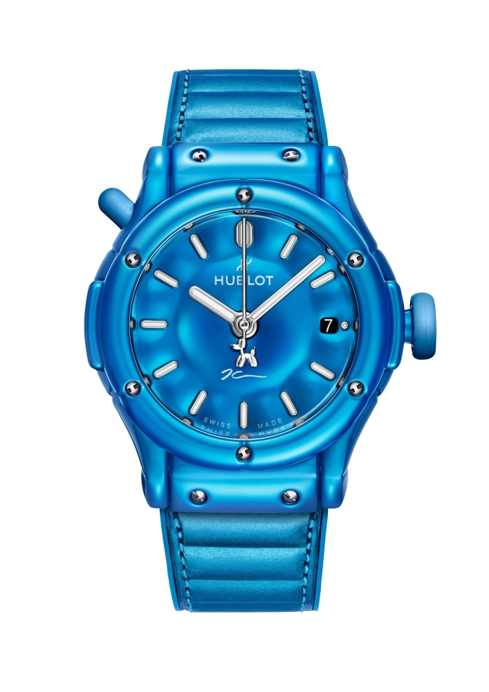 Parlak mavi seramik kasası ve uyumlu kayışı ile öne çıkan bu Hublot Classic Fusion kol saati, kadranındaki Jeff Koons'un imzası ve saniye ibresindeki ikonik Balon Köpek detayıyla sanatsal bir dokunuş sunarken, göstergeleri ve tarih penceresi net bir şekilde görülüyor.