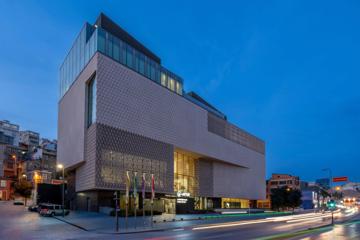 Beyoğlu Kültür Rotası'nın çağdaş sanatla buluştuğu Dolapdere'deki Arter binası, Grimshaw Architects tarafından tasarlanan kendine özgü desenli cephesi ve ışıklı cam bölümleriyle akşamın mavi göğü altında ve önünden geçen trafiğin uzun pozlama ışık izleriyle belirginleşiyor.