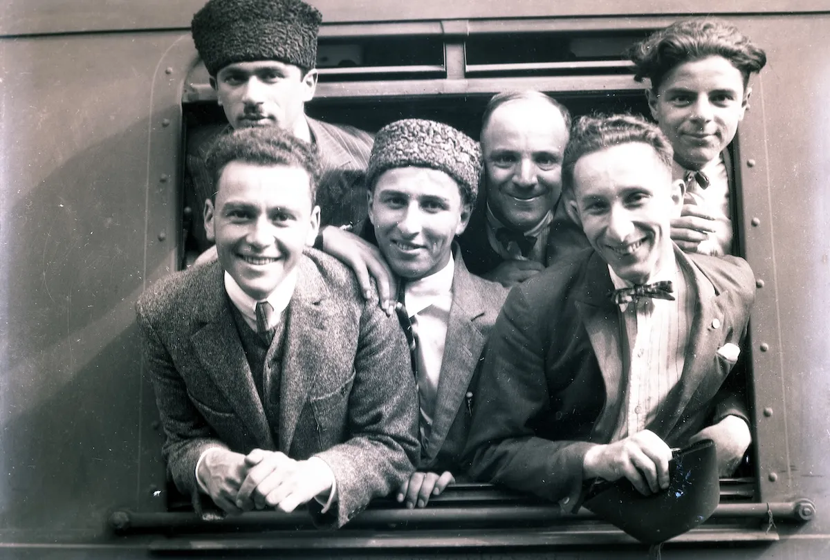 1925 İstanbul'da, Sirkeci Garı'ndan hareket eden bir trenin penceresinden gülümseyerek dışarı bakan, takım elbiseli, papyonlu ve geleneksel şapkalı altı kişilik sporcu kafilesi, Cumhuriyetin dinamik ruhunu ve coşkusunu taşıyor.