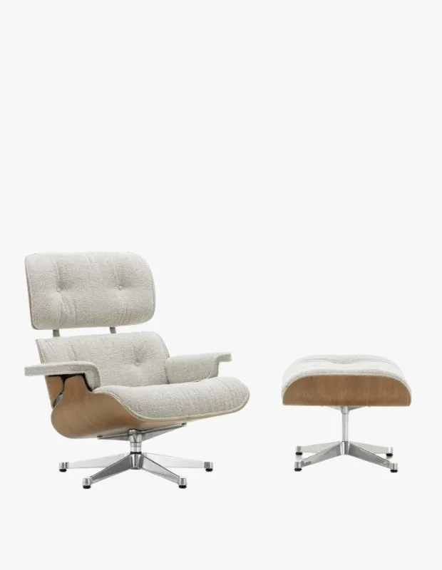 Fildişi rengi tüylü kumaş kaplı, düğmeli sırt ve oturma bölümlerine sahip, kavisli açık ahşap iskeletli modern bir Eames tekli koltuk ve uyumlu puf, döner metal ayaklar üzerinde beyaz stüdyo arka planında şık bir ürün önerisi olarak duruyor.