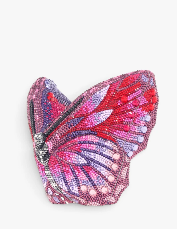 Judith Leiber imzalı, pembe, mor ve kırmızı tonlarında sayısız parlak kristalle süslenmiş, tümüyle kelebek şeklinde tasarlanmış lüks bir el çantası, markanın göz alıcı ve detaylı aksesuar işçiliğini vurguluyor.