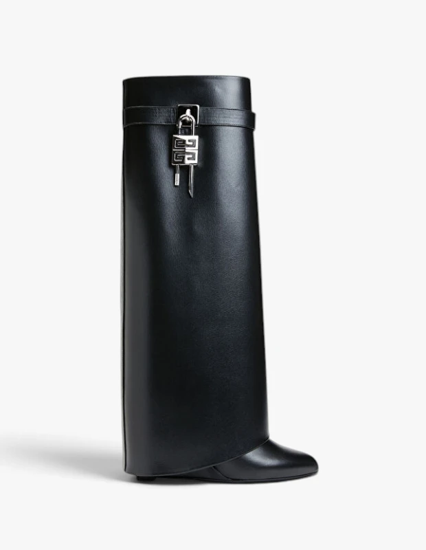 Beyaz bir arka plan üzerinde zarifçe konumlanmış, düz siyah deriden yapılmış, Givenchy logolu gümüş renkli asma kilit ve sallanan anahtar detaylarıyla süslenmiş, benzersiz drapeli bacak kısmına sahip bu modern çizme, kış ayakkabı trendlerinin iddialı bir örneğidir.