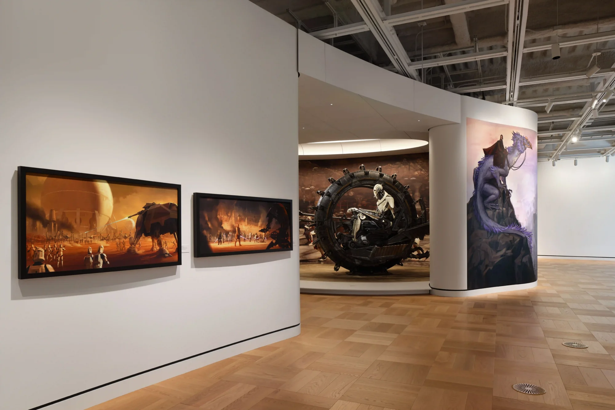 Lucas Museum of Narrative Art'ın geniş bir galerisinde, ahşap parke zemin üzerinde, Star Wars serisinden General Grievous'un tekerlekli motosiklet heykeli, duvarlarda serinin dünyasından savaş sahnelerini ve fantastik yaratıkları betimleyen konsept çizim ve büyük boy dijital baskılar, görsel hikâye anlatıcılığının zenginliğini yansıtıyor.