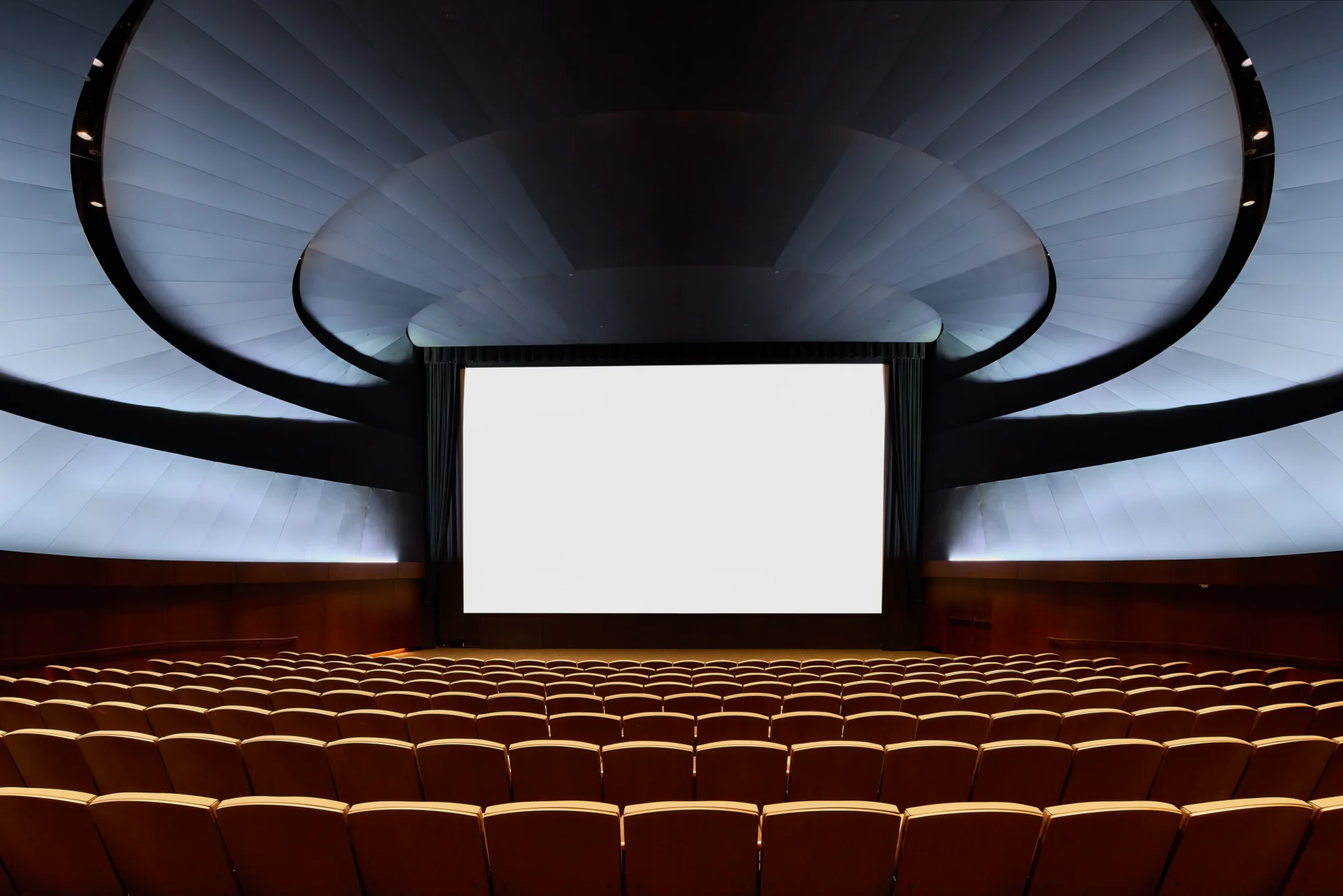 George Lucas’ın biriktirdiği dünyaları ve anlatı sanatının gücünü sunmaya hazırlanan Lucas Museum of Narrative Art’ın modern sinema salonlarından birinde, izleyicileri bekleyen geniş beyaz perde ve kavisli, aydınlatmalı tavanıyla boş kahverengi koltuklar görülüyor.