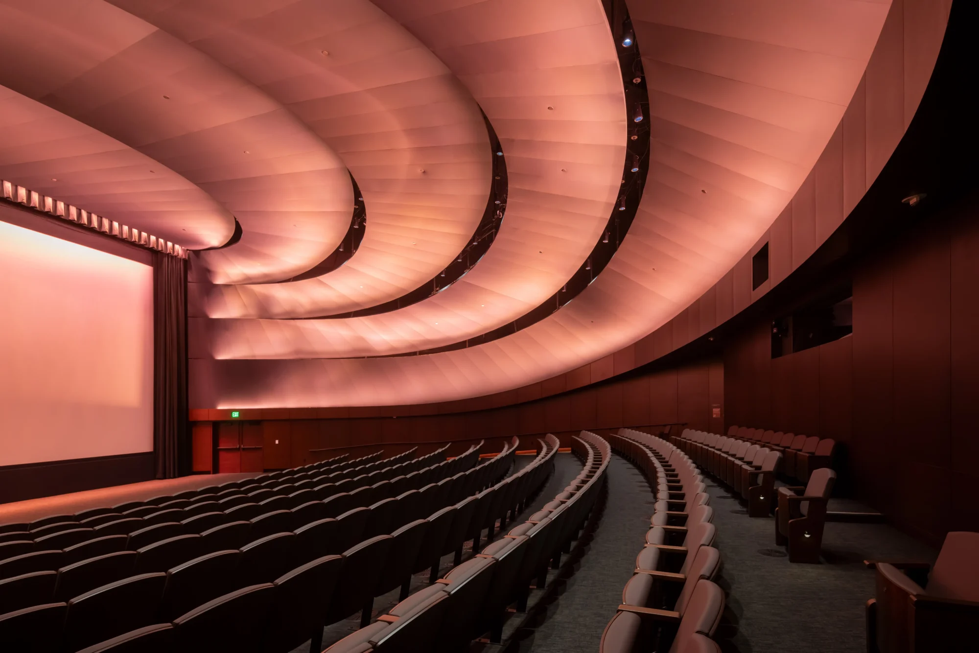George Lucas’ın kurduğu Lucas Museum of Narrative Art bünyesindeki modern bir sinema salonunun iç görünümü, boş, kavisli koltuk sıraları, devasa perdesi ve dalgalı, sıcak ışıkla aydınlatılmış mimari tavanıyla görsel hikâye anlatıcılığının ve sinemanın büyülü dünyalarına kapı aralıyor.