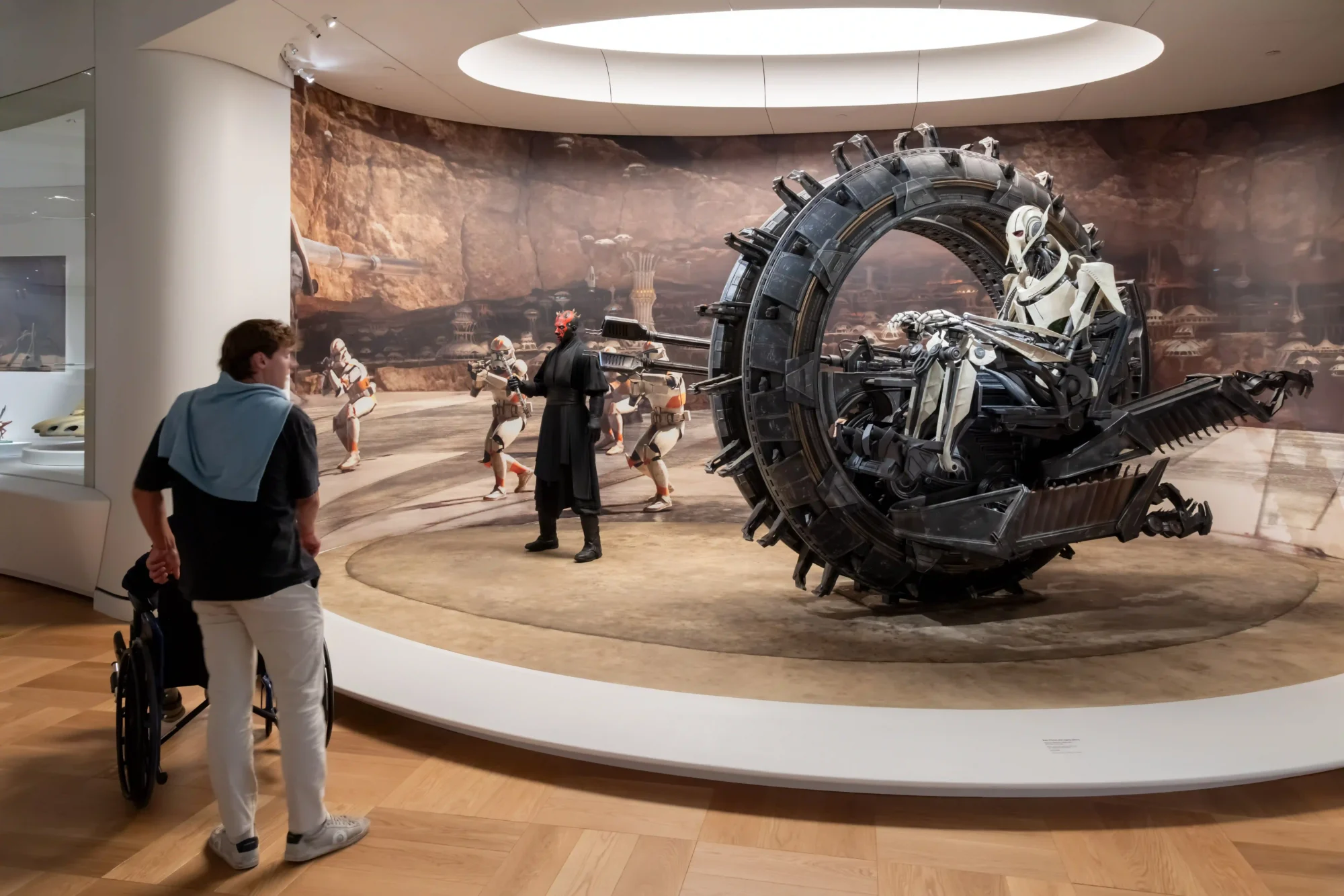 Lucas Museum of Narrative Art'taki Star Wars in Motion sergisinde, General Grievous'un tekerlekli aracı, Darth Maul ve Klon Birlikleri karakterlerinin gezegen manzaralı bir duvar resmi önünde sergilendiği, George Lucas'ın biriktirdiği dünyalara ait sürükleyici bir görsel anlatım sunuluyor.