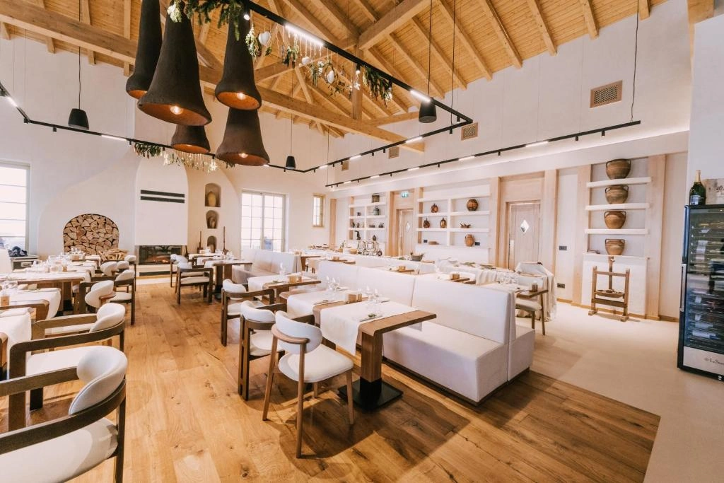 Yüksek ahşap tavanlı, açık renk ahşap zeminli, aydınlık ve ferah restoranda, beyaz örtülü masalar, beyaz banketler ve şömine kenarındaki odun yığınıyla modern ve rustik unsurları birleştiren şık bir yemek alanı göze çarpıyor.