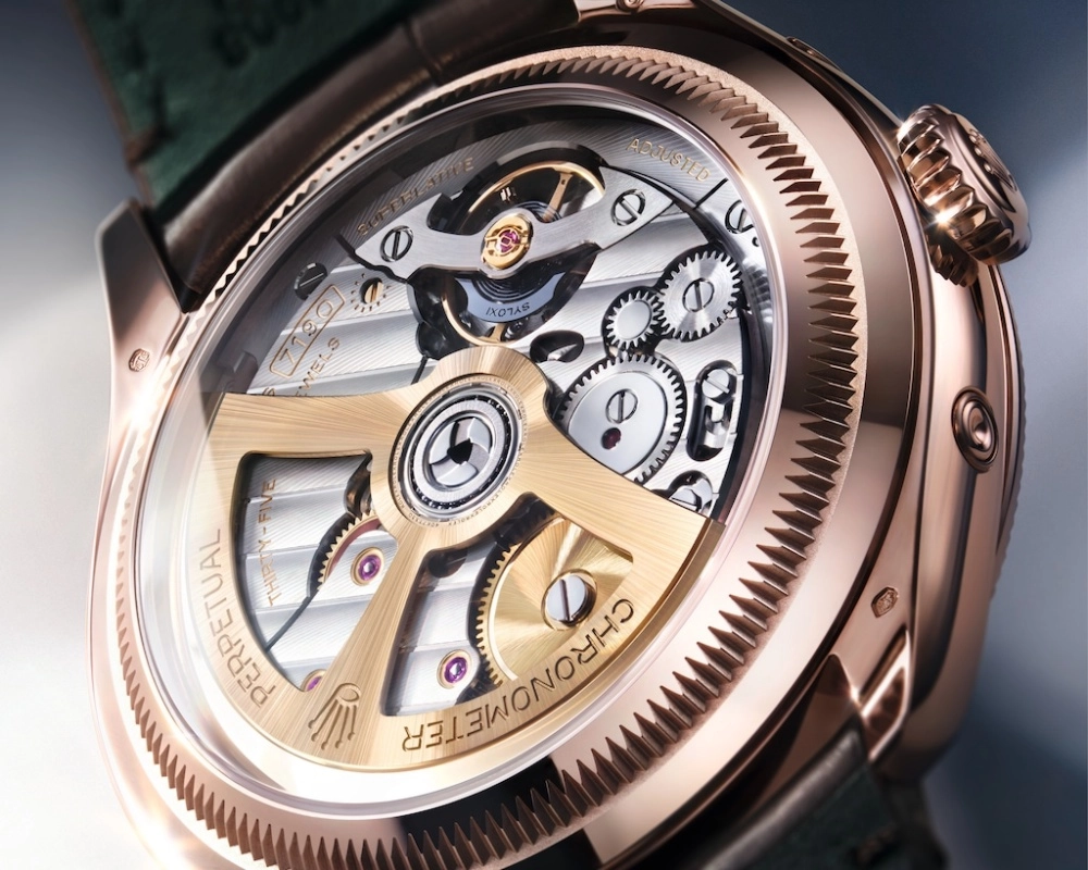 Yakın çekim görüntüde, lüks Rolex Perpetual Padellone saatin safir arka kapağından görünen, altın rengi rotorlu ve karmaşık çark detaylarına sahip hassas Calibre 7190 mekanizması tüm ihtişamıyla sergileniyor.