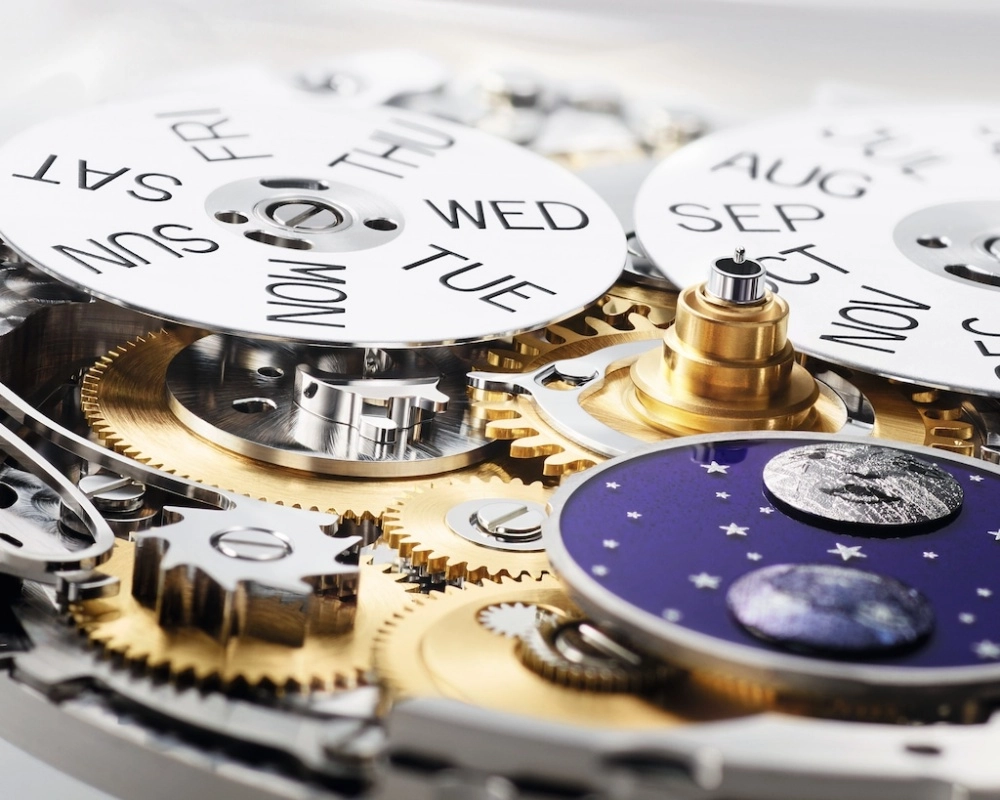 Rolex Perpetual Padellone mekanizmasının yakından görünümü, gün ve ayları gösteren beyaz diskler, mor zemin üzerindeki parlak yıldızlar ve detaylı ay evreleri kadranı ile birlikte hassas altın ve gümüş rengi dişlilerle bezeli karmaşık iç yapısını gözler önüne seriyor.