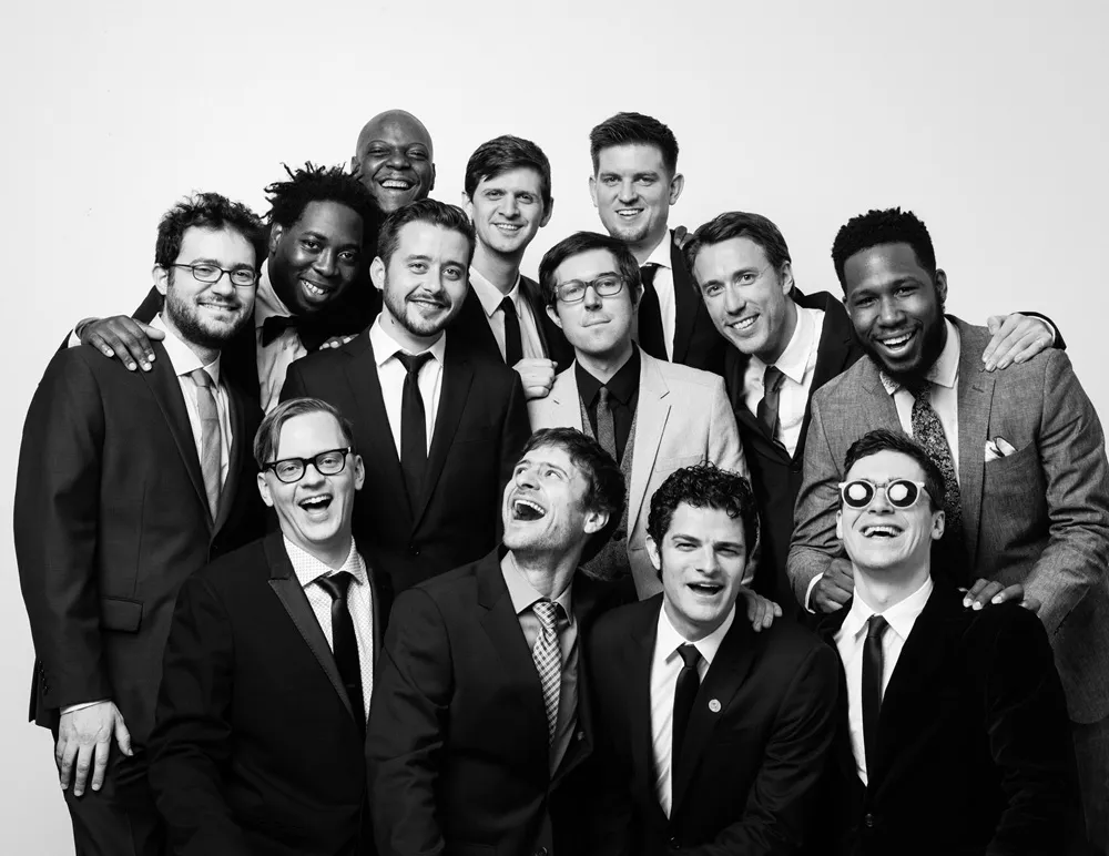 Beş Grammy ödüllü Snarky Puppy grubunun üyeleri, siyah beyaz bir fotoğrafta takım elbiseleri içinde, neşeli ve enerjik halleriyle bir araya gelmiş, samimi gülümsemelerle objektife bakıyor.