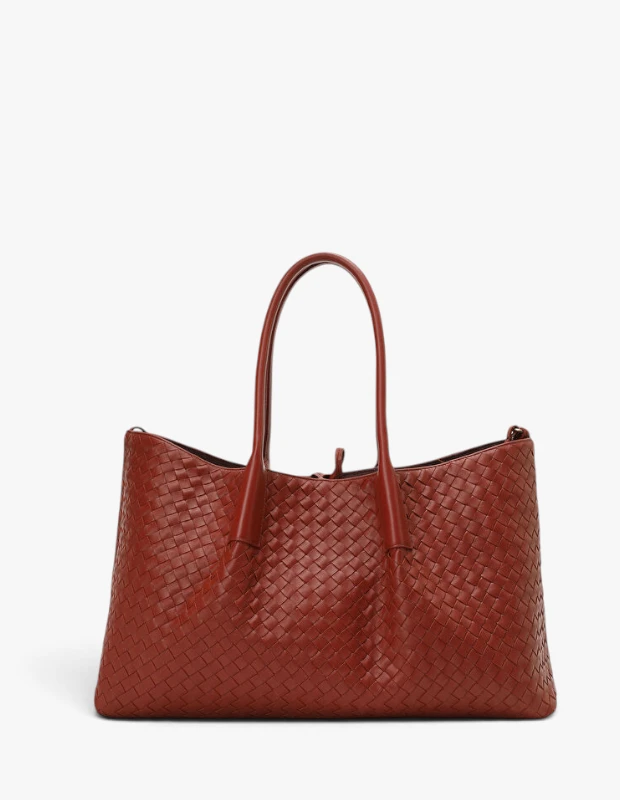 Geniş ve kiremit rengi örgü deriden yapılmış, Bottega Veneta'nın ikonik Intrecciato tekniğiyle üretilmiş bu şık alışveriş çantası, iki adet uzun sapıyla sonbahar-kış çanta trendleri arasında fonksiyonel ve göz alıcı bir seçenek sunuyor.