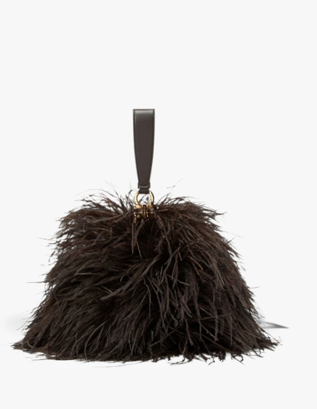 Sonbahar-kış çanta trendleri arasında öne çıkan, koyu kahverengi bol tüylerle kaplı, kısa deri bilek askısı ve altın rengi metal detaylara sahip Ferragamo marka modern bir clutch çanta beyaz bir zeminde sergileniyor.