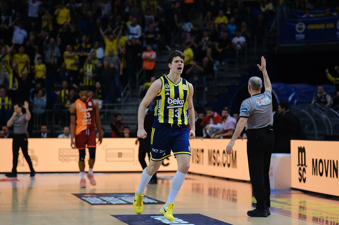 Fenerbahçe Beko formasıyla parkede yumrukları sıkılı, ağzı açık bir şekilde coşkuyla koşan Tarık Biberović, kazanılan önemli bir sayının ardından sevincini yaşarken arkasında rakip takım oyuncusunu ve tezahürat yapan taraftarları bırakıyor.