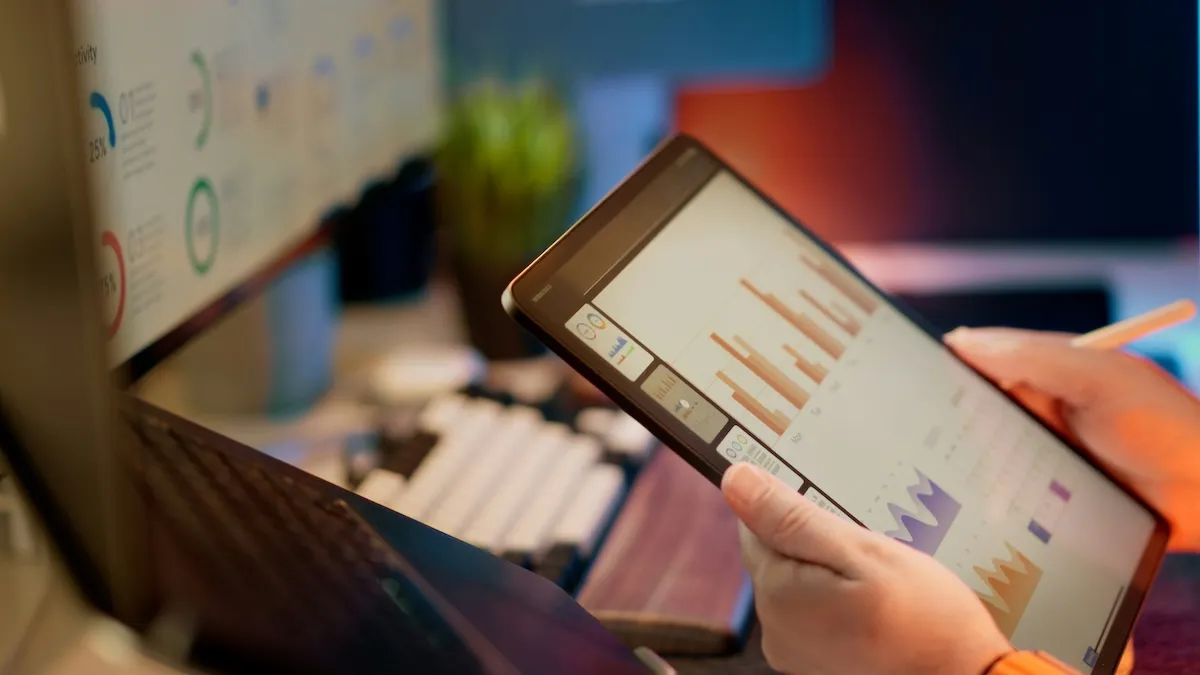 Finansal verileri titizlikle inceleyen bir kişinin eli, performans grafikleri ve oranları gösteren bir tableti yönlendirirken, arka planda benzer analiz ekranlarının olduğu bir bilgisayar monitörü belirginleşiyor ve yatırım fonu seçimi için detaylı araştırmanın kritik rolünü sergiliyor.