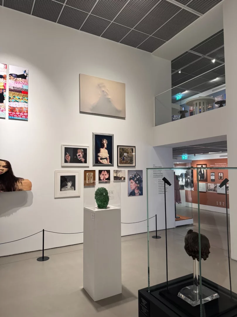 Modern bir sanat galerisinde, Koç Topluluğu'nun sanata verdiği değeri ve yüzyılın izlerini yansıtan, duvarda asılı büyük soyut ve fotoğraf eserleri ile podyum ve cam vitrinlerde sergilenen çeşitli büst ve heykel çalışmalarıyla dolu geniş bir sergi alanı izleyiciyi karşılıyor.